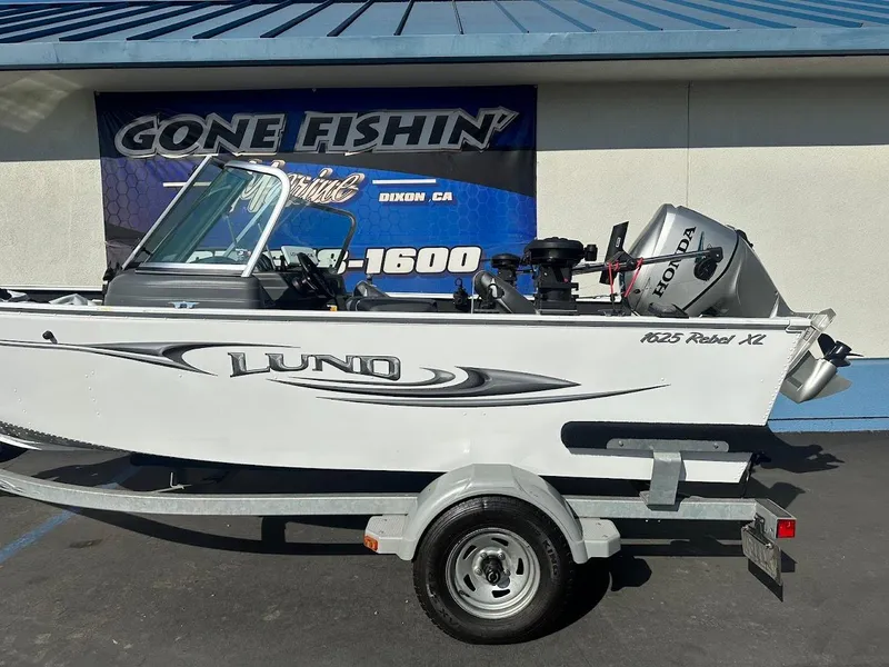 Slide: The Image of 2011 Lund 1625 Rebel XL Sport boat on trailer, parked outside a fishing store. - 6