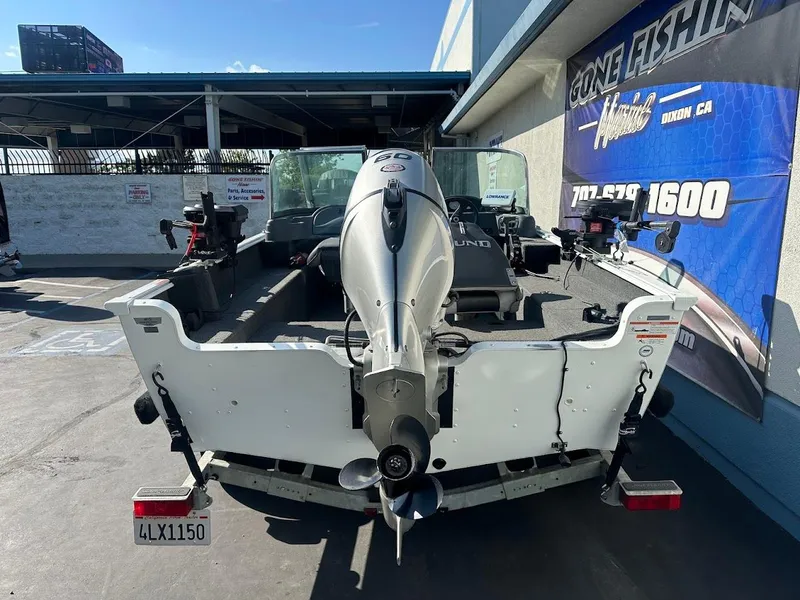 Slide: The Image of 2011 Lund 1625 Rebel XL Sport boat, rear view, parked outdoors near a fishing shop. - 8