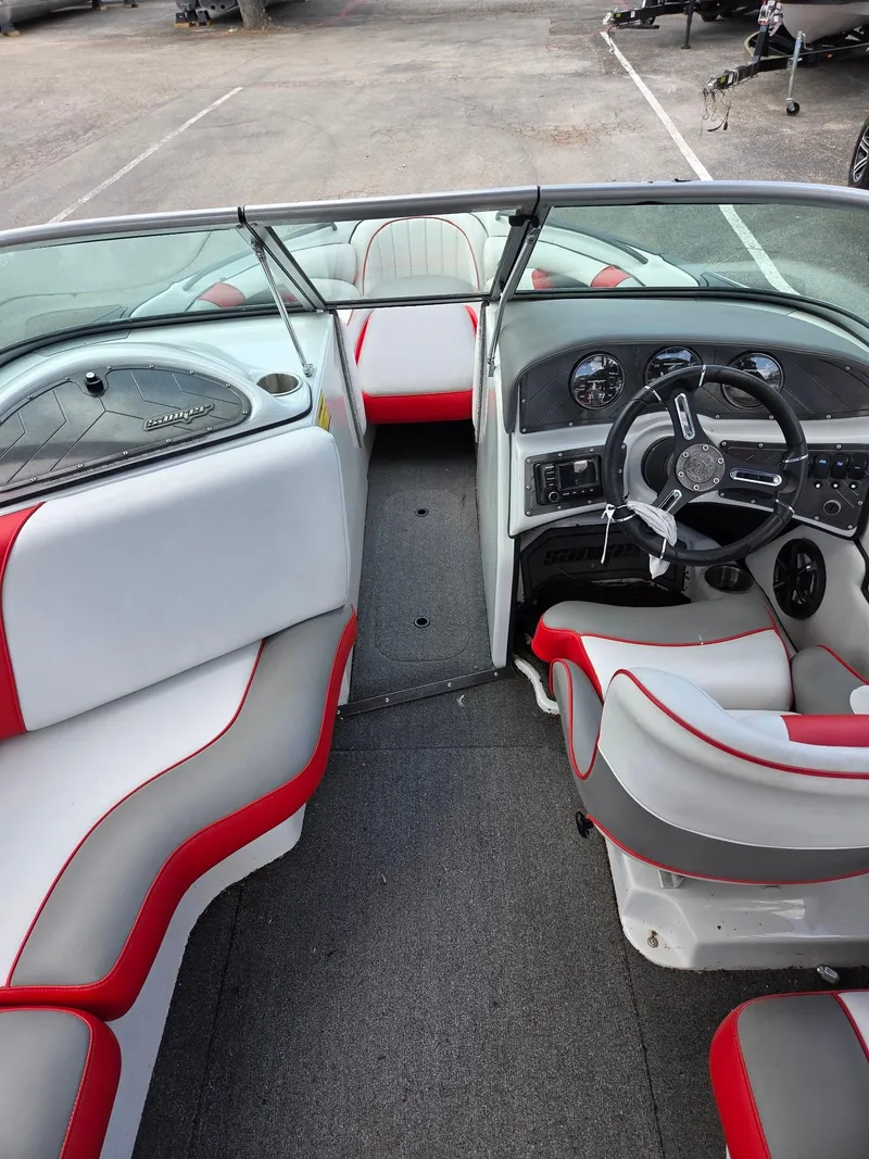 Slide: The Image of 2021 Sanger V215 S boat interior with red and gray seating, steering wheel, and dashboard. - 6