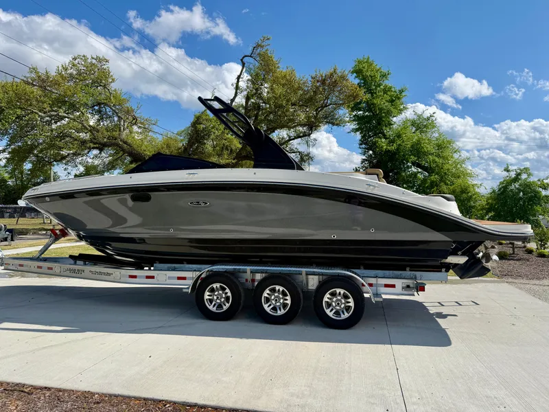 Slide: The Image of 2018 Sea Ray SDX 270 boat on a trailer, parked outdoors under a clear blue sky. - 0