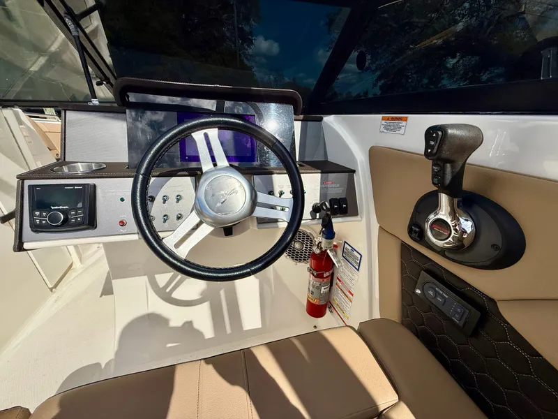 Slide: The Image of 2018 Sea Ray SDX 270 helm with steering wheel, controls, and fire extinguisher. - 11