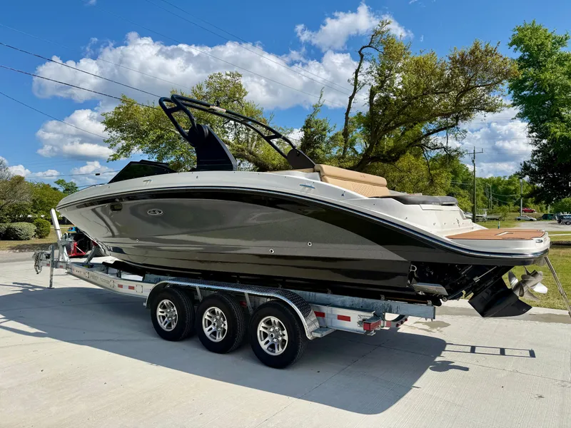 Slide: The Image of 2018 Sea Ray SDX 270 boat on a trailer, parked outdoors under a clear blue sky. - 2