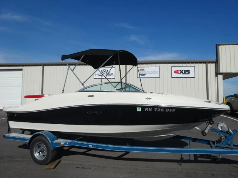 Slide: The Image of 2007 Sea Ray 185 Sport boat on trailer, parked outside a building under clear blue sky. - 1