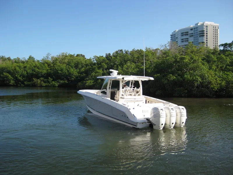 Slide: The Image of 2018 Boston Whaler 380 Outrage boat on calm water near lush greenery and buildings. - 3