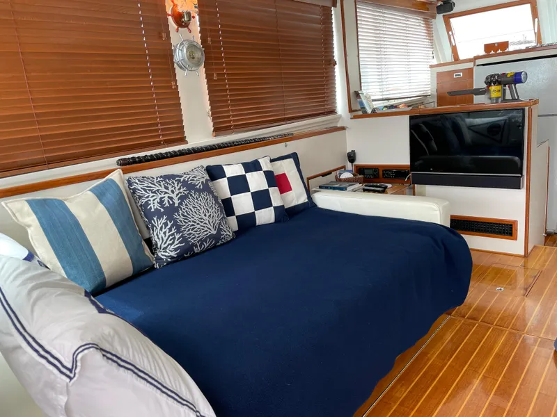 Slide: The Image of 1966 Huckins Sportsman interior with cozy seating, nautical-themed pillows, and wooden flooring. - 12