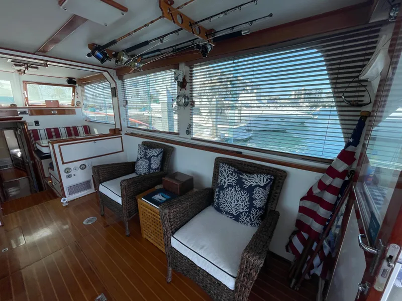 Slide: The Image of 1966 Huckins Sportsman interior with wicker chairs, nautical decor, and fishing rods. - 14