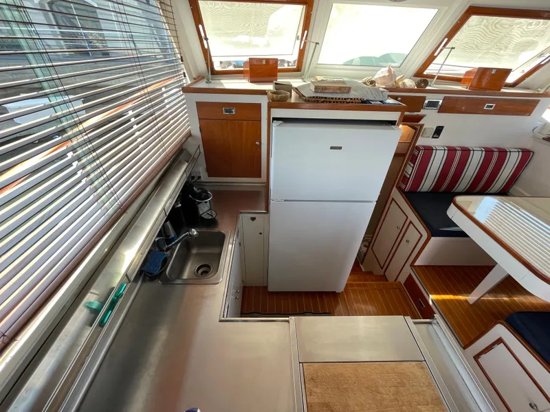 Slide: The Image of 1966 Huckins Sportsman yacht interior with kitchen, fridge, and seating area. - 18