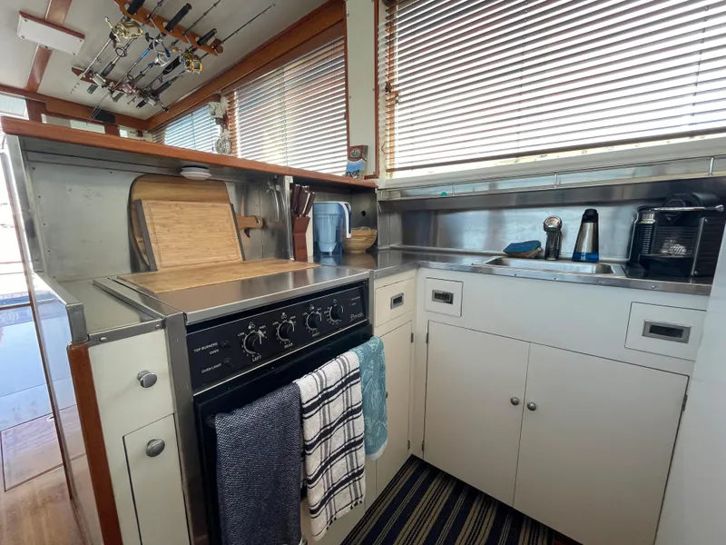 Slide: The Image of 1966 Huckins Sportsman boat kitchen with stove, cabinets, and striped rug. - 20