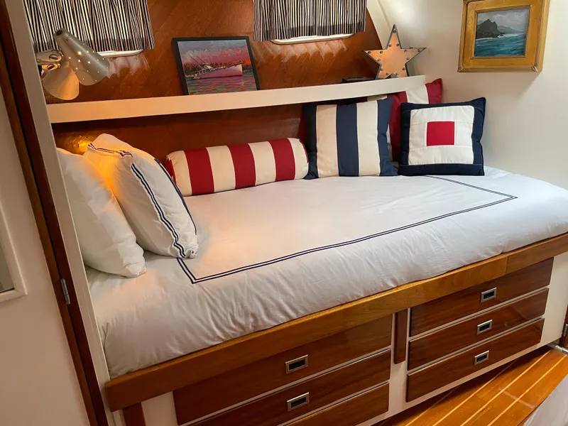 Slide: The Image of 1966 Huckins Sportsman cabin with nautical-themed bedding and wooden storage drawers. - 21