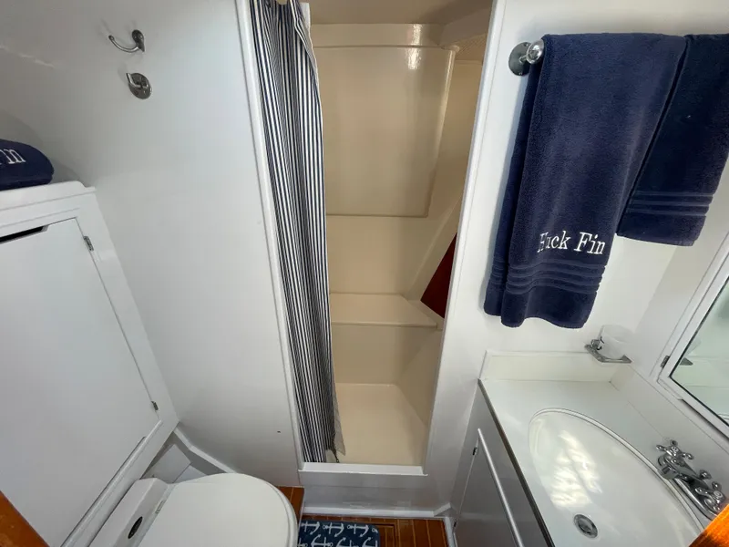 Slide: The Image of Bathroom interior of a 1966 Huckins Sportsman boat, featuring shower, sink, and towels. - 24