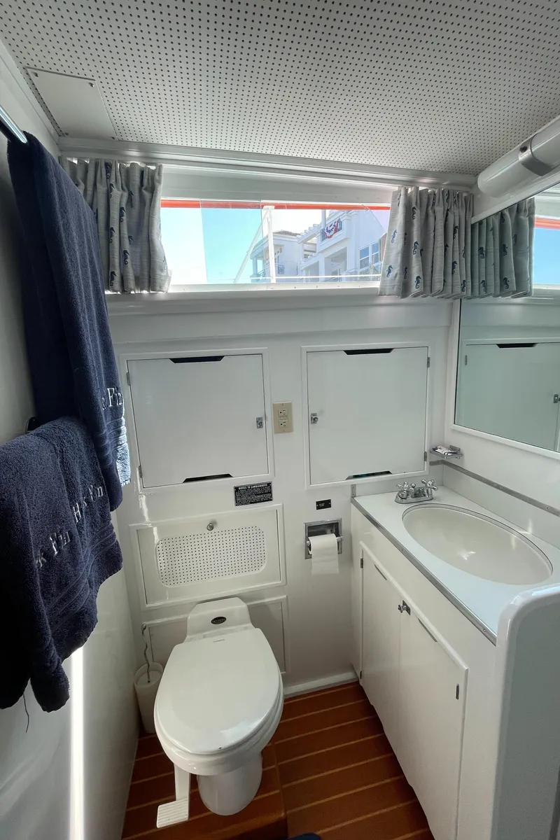 Slide: The Image of 1966 Huckins Sportsman boat bathroom with white fixtures, wooden floor, and natural light. - 27