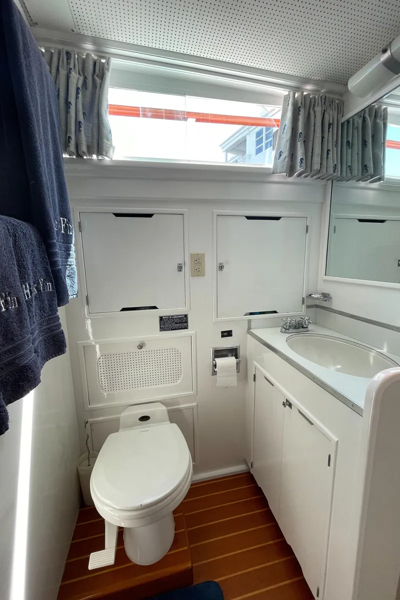 Slide: The Image of 1966 Huckins Sportsman yacht bathroom with toilet, sink, and storage cabinets. - 30