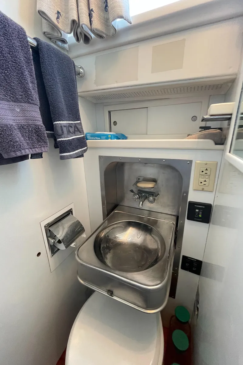 Slide: The Image of Compact bathroom in a 1966 Huckins Sportsman boat, featuring a stainless steel sink and modern amenities. - 33