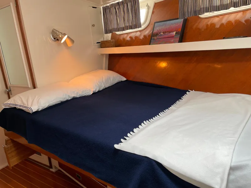 Slide: The Image of 1966 Huckins Sportsman cabin with cozy bed, wooden accents, and nautical decor. - 36