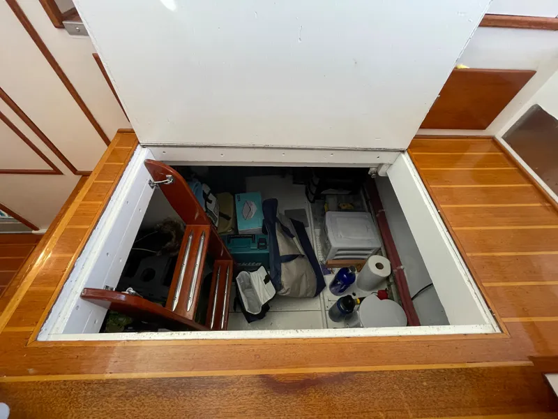 Slide: The Image of Storage compartment on a 1966 Huckins Sportsman boat, featuring wooden flooring and various stored items. - 37