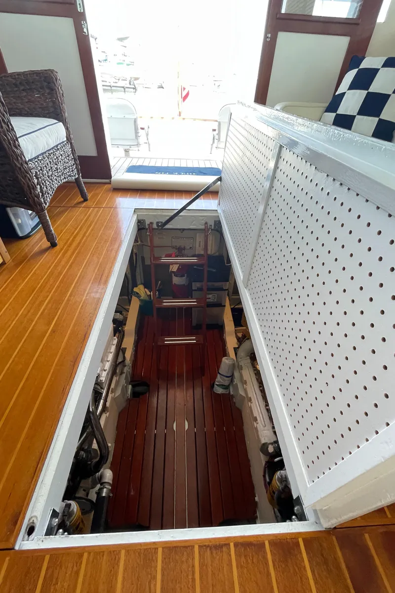 Slide: The Image of 1966 Huckins Sportsman yacht interior with open engine compartment, wooden flooring, and nautical decor. - 38