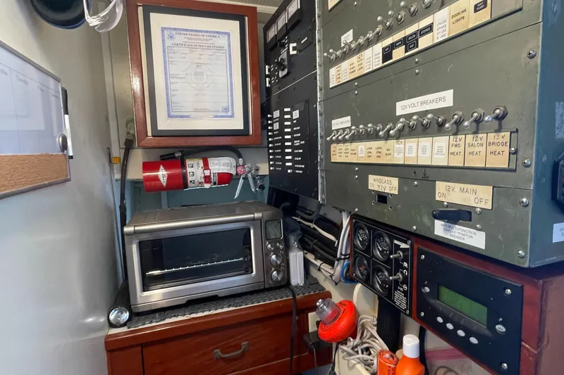 Slide: The Image of Control panel and equipment inside a 1966 Huckins Sportsman boat, featuring a toaster oven and fire extinguisher. - 41