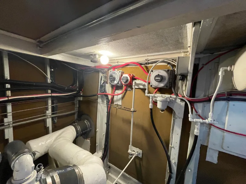 Slide: The Image of Engine room of a 1966 Huckins Sportsman boat, featuring pipes and electrical wiring. - 43