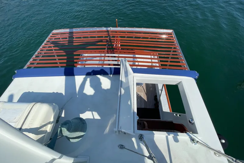 Slide: The Image of 1966 Huckins Sportsman boat deck with open hatch, overlooking calm water. - 49