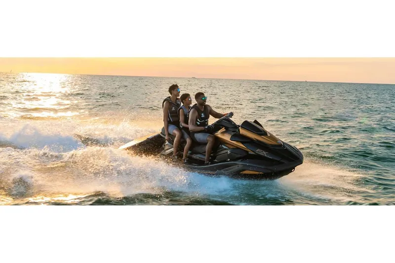 Slide: The Image of 2024 Yamaha FX Limited SVHO jet ski with three riders on ocean at sunset. - 9