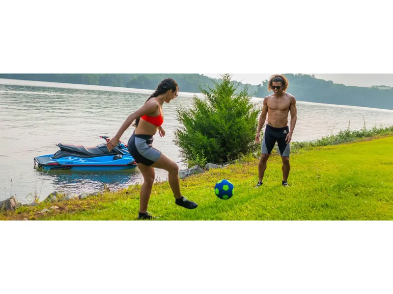 Slide: The Image of Two people playing soccer near a lake with a 2024 Yamaha VX Deluxe jet ski. - 7