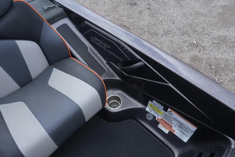 Slide: The Image of 2018 Skeeter ZX200 boat interior with gray and black seating, cup holder, and safety labels. - 18