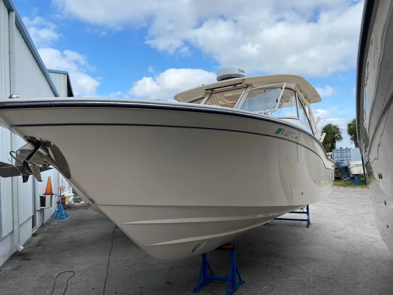 Slide: The Image of 2022 Grady-White Freedom 325 boat on stands, dockside view, under a partly cloudy sky. - 2