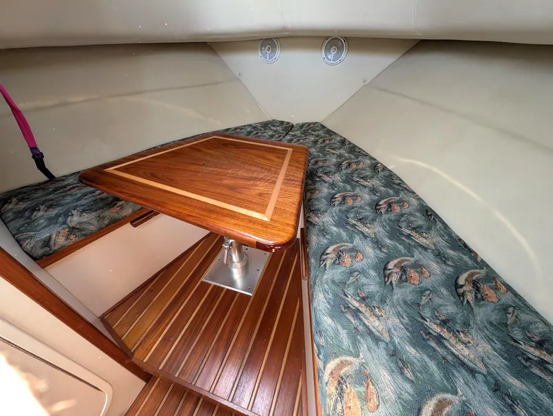 Slide: The Image of 2001 Pursuit 3070 Offshore Center Console cabin with wood table and patterned seating. - 24