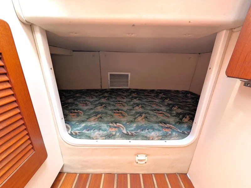 Slide: The Image of 2001 Pursuit 3070 Offshore Center Console cabin with patterned bedding and wooden accents. - 25