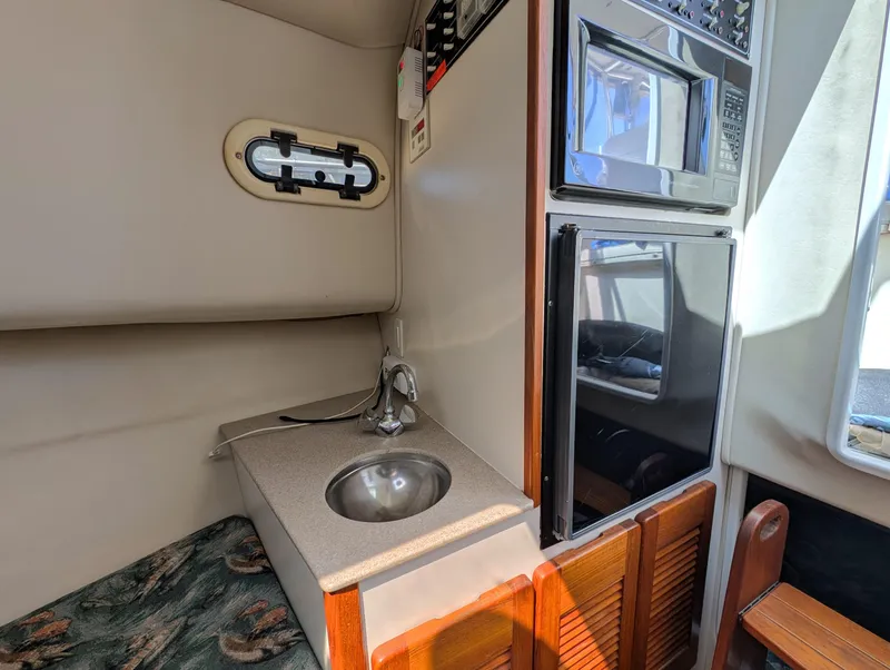 Slide: The Image of 2001 Pursuit 3070 Offshore Center Console interior with sink, microwave, and storage. - 26