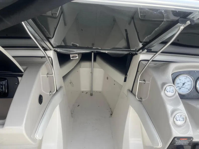 Slide: The Image of 2008 Larson 206 Sensa boat interior with open storage compartment and dashboard gauges. - 12