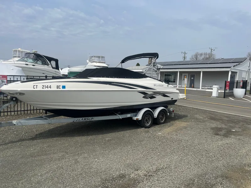Slide: The Image of 2008 Larson 206 Sensa boat on trailer, parked near marina buildings. - 4