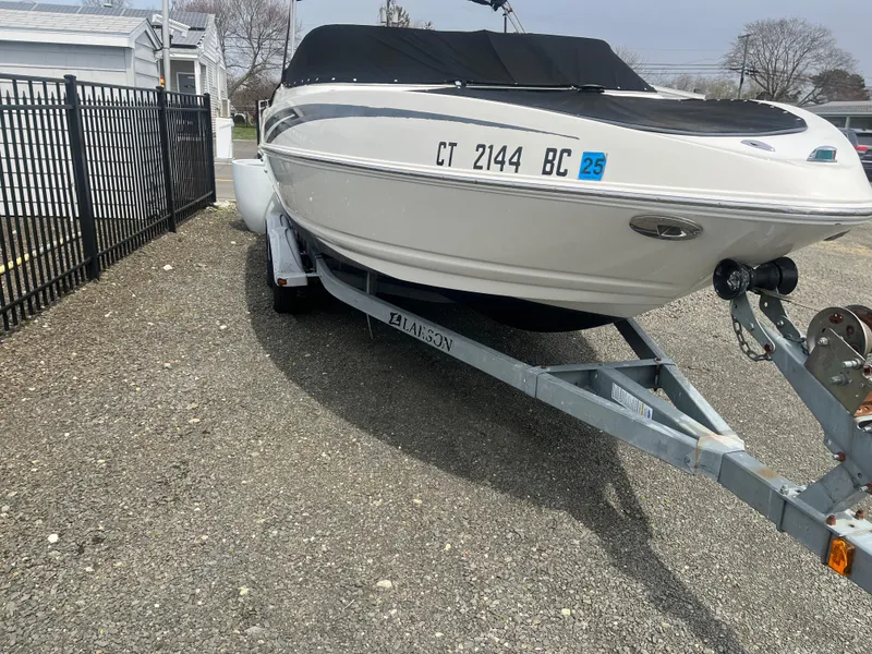 Slide: The Image of 2008 Larson 206 Sensa boat on trailer, parked on gravel near a fence. - 3