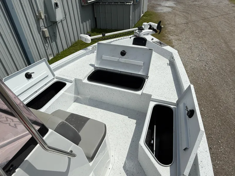 Slide: The Image of 2022 Express H20 boat with open storage compartments and seating, parked near a metal building. - 10