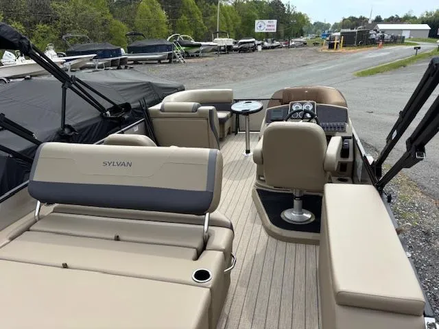 Slide: The Image of 2025 Sylvan X-3 CLZ pontoon boat interior with beige seating and helm, parked outdoors. - 14