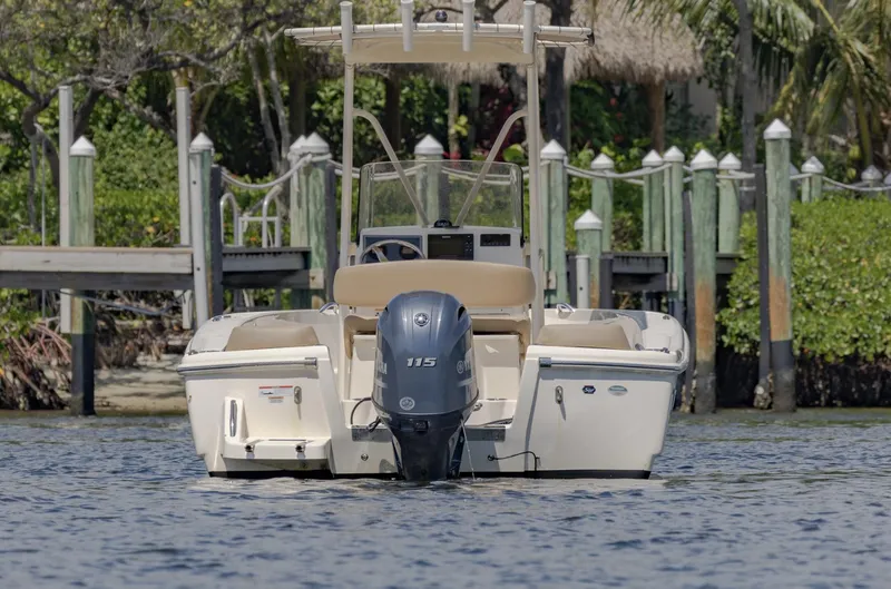 Slide: The Image of 2023 Scout 195 Sportfish boat with outboard motor, docked in a serene marina setting. - 3