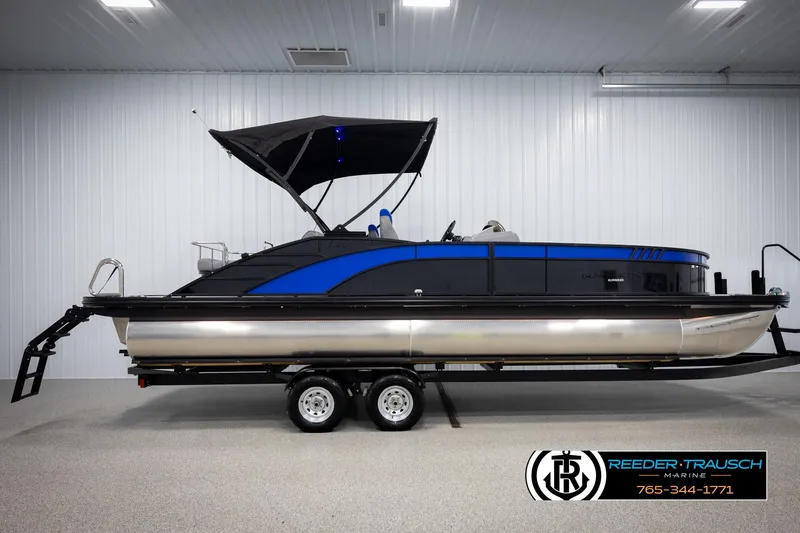 Slide: The Image of 2025 Bennington 25 LTSBSE pontoon boat with blue accents on a trailer indoors. - 4