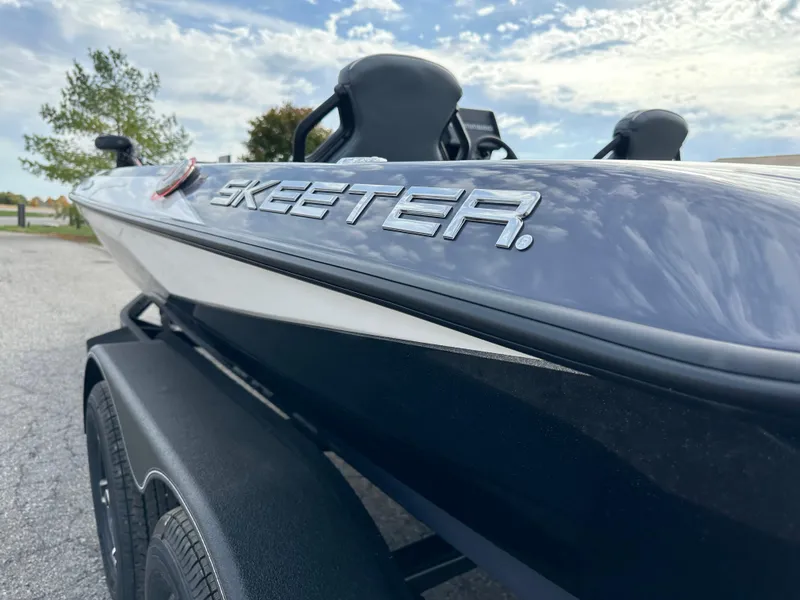 Slide: The Image of 2024 Skeeter ZXR19 boat side view with logo, parked outdoors under a blue sky. - 7