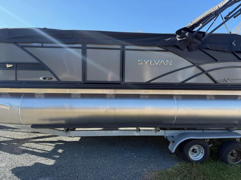 Slide: The Image of 2025 Sylvan X-3 CLZ pontoon boat on trailer, side view, black and silver design. - 1