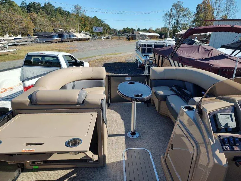 Slide: The Image of 2025 Sylvan X-3 CLZ pontoon boat interior with seating and table, parked outdoors. - 10