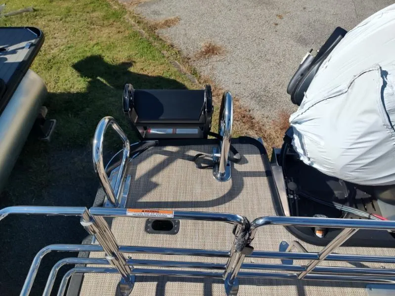 Slide: The Image of 2025 Sylvan X-3 CLZ boat deck with motor and railing, parked on grass and pavement. - 5