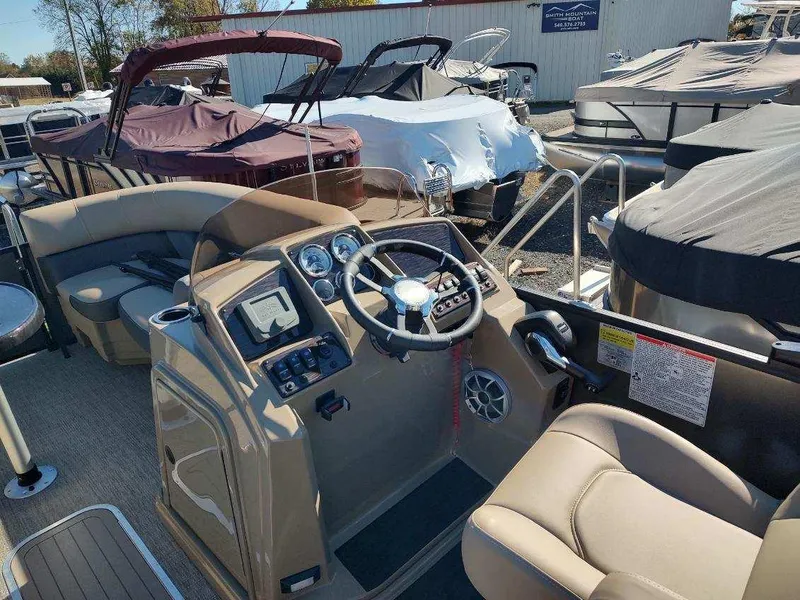 Slide: The Image of 2025 Sylvan X-3 CLZ boat interior with steering wheel and dashboard, docked among other boats. - 9