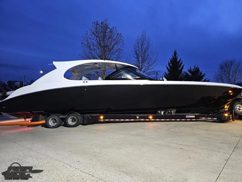 Slide: The Image of 2023 Mystic Powerboats M5200 on trailer at dusk, sleek black and white design. - 5