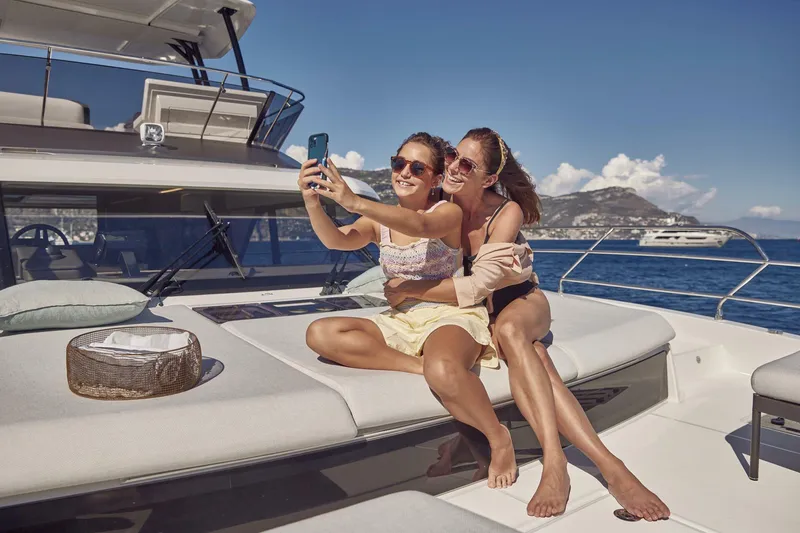 Slide: The Image of Two people taking a selfie on a 2025 Prestige M48 yacht, enjoying a sunny day at sea. - 17