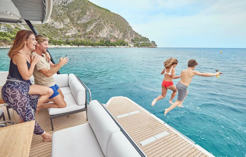 Slide: The Image of Family enjoying a day on a 2025 Prestige M48 yacht, kids jumping into the sea. - 2