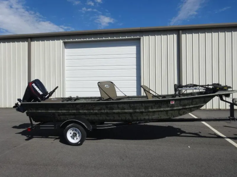 Slide: The Image of 2014 War Eagle 1542 boat on trailer, parked outside a metal building. - 1