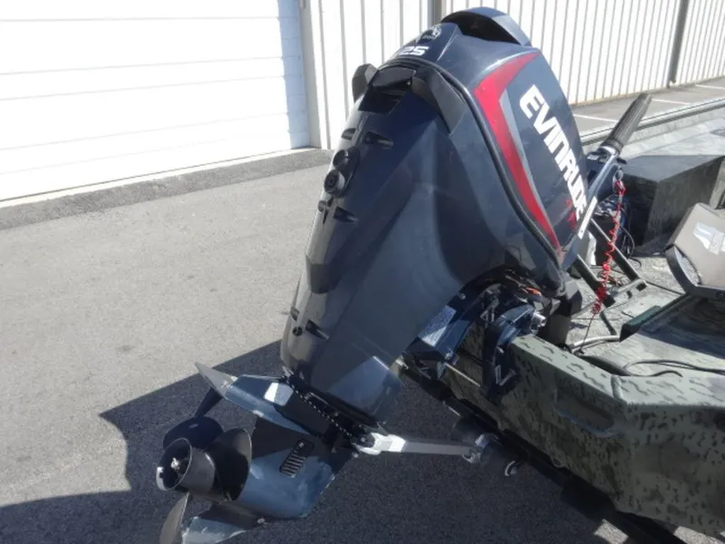 Slide: The Image of 2014 War Eagle 1542 boat with Evinrude outboard motor, parked on pavement. - 2