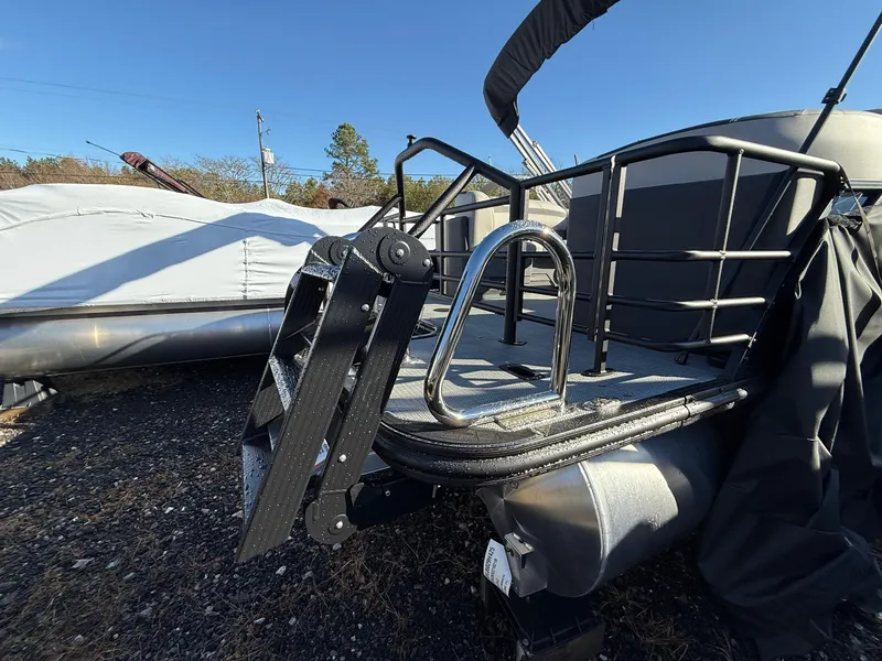 Slide: The Image of 2025 Sylvan L-3 LZ pontoon boat with ladder and railing, parked outdoors. - 27