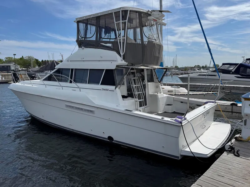 The Image of 1997 Silverton 41 Convertible yacht docked at marina under clear blue sky. - 0
