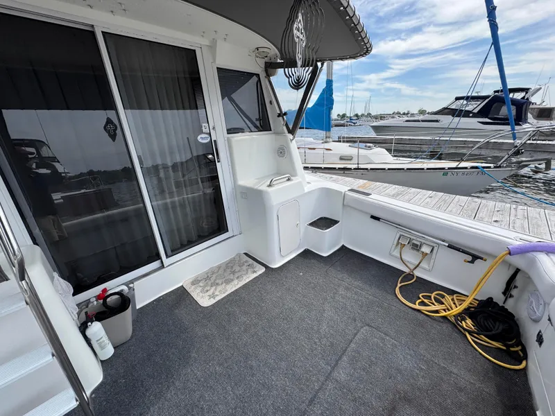 Slide: The Image of 1997 Silverton 41 Convertible yacht deck with marina view, featuring seating and storage. - 15